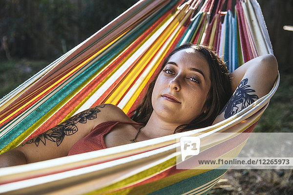 Portrait einer jungen Frau mit Tattoo in der Hängematte liegend