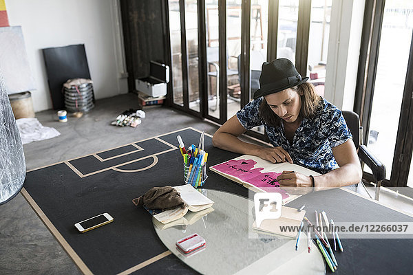 Künstler bei der Arbeit  Zeichnen in einem Notizbuch in seinem Loft-Studio