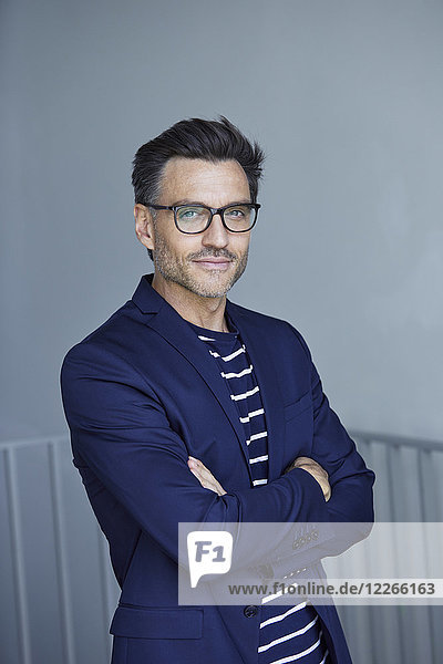 Portrait of stylish businessman with stubble wearing blue suit and glasses