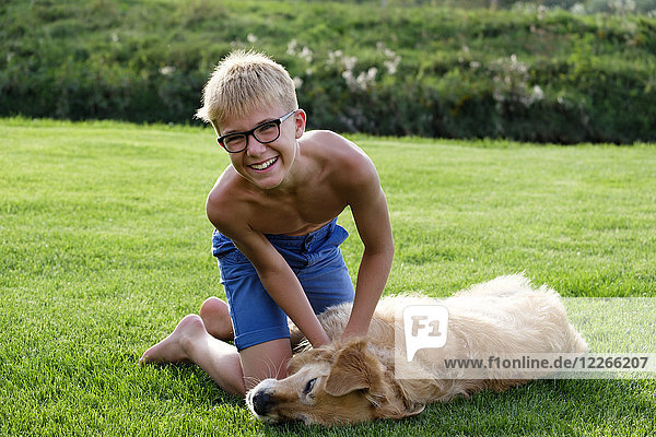 Fröhlicher Teenager spielt mit Hund im Gras