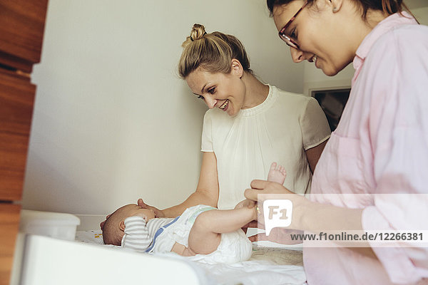 Midwife showing mother how to change diapers of newborn baby