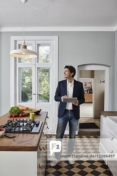 Man using tablet in kitchen looking at ceiling lamp