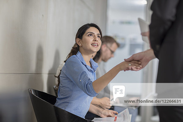 Woman in office waiting area shaking hands