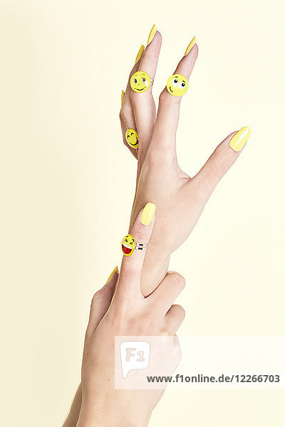 Nahaufnahme von Frauenhänden mit Emojis an Ringen