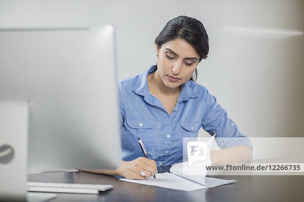Businesswoman taking notes at desk in office