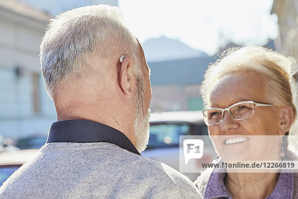 Nahaufnahme eines älteren Mannes mit Hörgerät im Gespräch mit einer älteren Frau