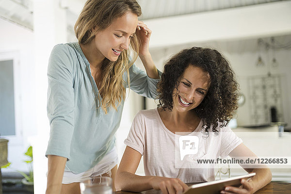Two smiling women at home using tablet