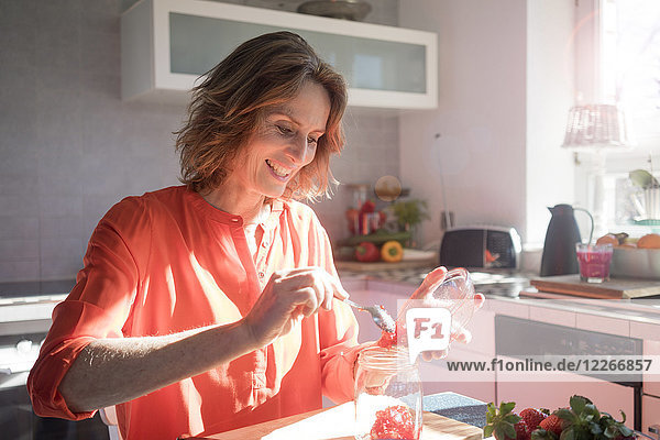 Lächelnde Frau macht Erdbeermarmelade in der Küche zu Hause