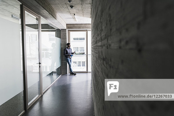 Businessman standing at the window holding cell phone