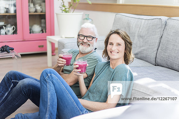 Glückliches reifes Paar mit gesunden Getränken im Wohnzimmer zu Hause