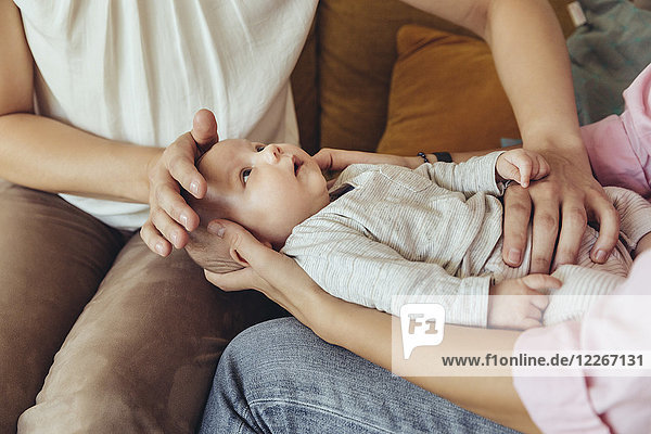 Hebamme und Mutter geben dem Neugeborenen eine Bauchmassage zur Unterstützung der Verdauung.