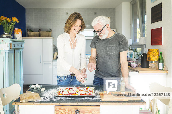 Ein reifes Paar bereitet eine Pizza in der Küche zu Hause vor.