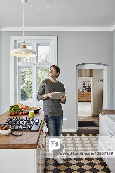 Man using tablet in kitchen looking at ceiling lamp