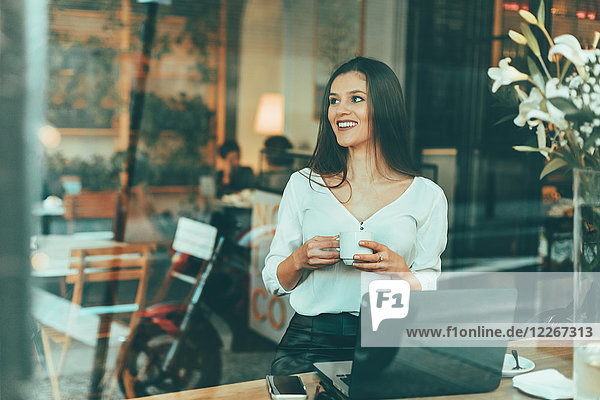 Porträt einer lachenden jungen Frau  die in einem Coffee-Shop wartet.