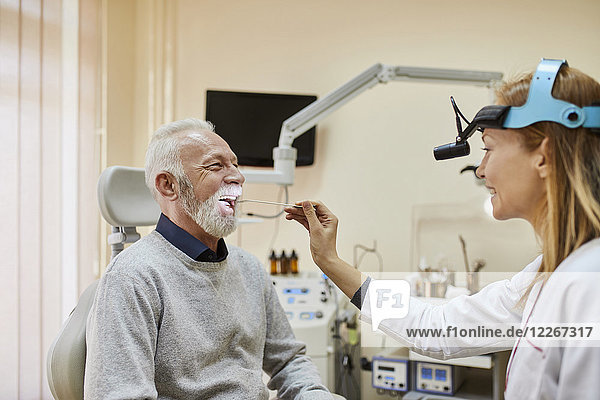 ENT physician examining mouth of a senior man