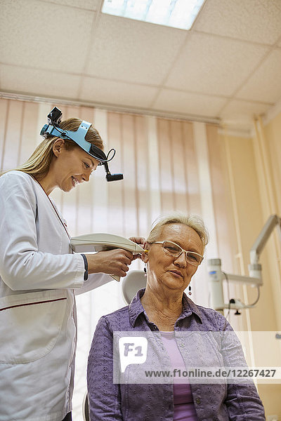 HNO-Arzt untersucht Ohr einer älteren Frau