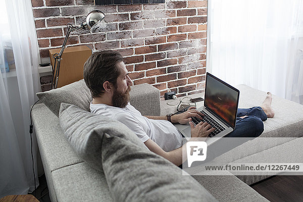 Man sitting on the couch at home using laptop