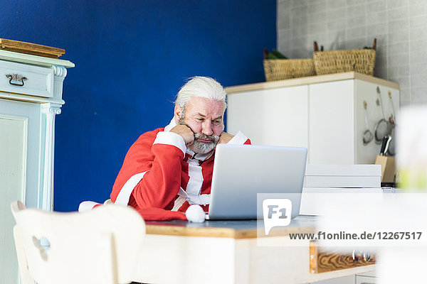 Frustrierte Weihnachtsmann mit Laptop zu Hause