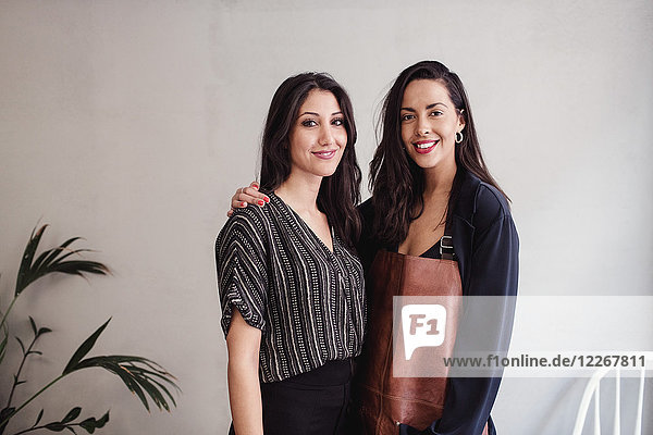 Portrait of smiling multi-ethnic female coworkers standing against wall at workshop