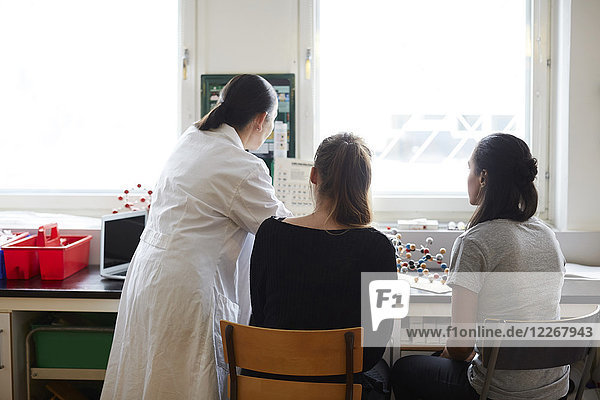 Rückansicht eines reifen Chemielehrers mit jungen Schülern im Klassenzimmer