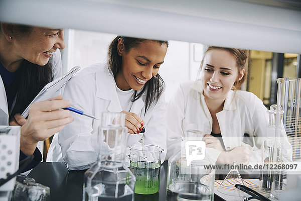 Lächelnde multiethnische Universitätsstudenten mit ausgereifter Lehrer-Mischlösung im Labor