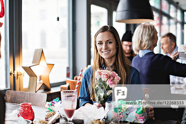 Portrait of smiling woman with gifts at dining table in restaurant