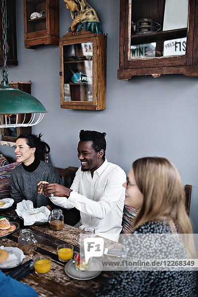 Fröhliche multiethnische Freunde beim Brunch am Tisch im Restaurant