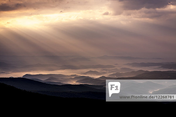 Die Sonne scheint durch die Wolken über die Silhouetten der in Morgennebel gehüllten Hügel  Linville  North Carolina  USA