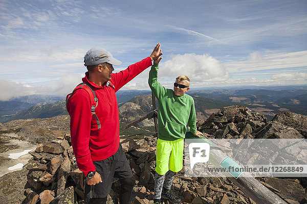 Father and son high-five upon reaching summit of Jim Kelly Peak  Merritt  British Columbia  Canada