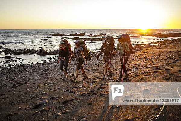 Vier Rucksacktouristinnen wandern bei Sonnenuntergang am Strand entlang  Lost Coast Trail  Kings Range National Conservation Area  Kalifornien  USA