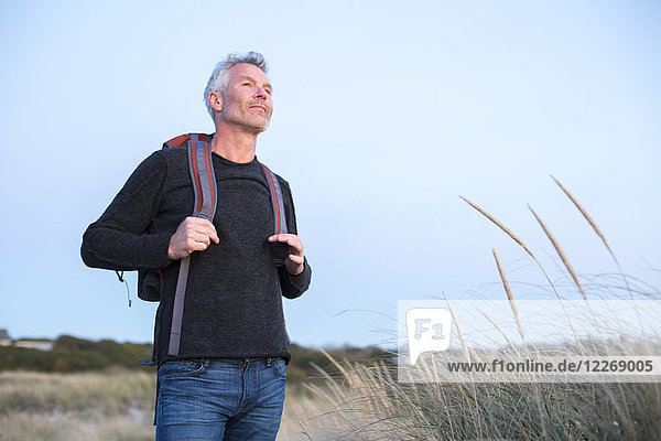 Mature man with gray hair and backpack at beach