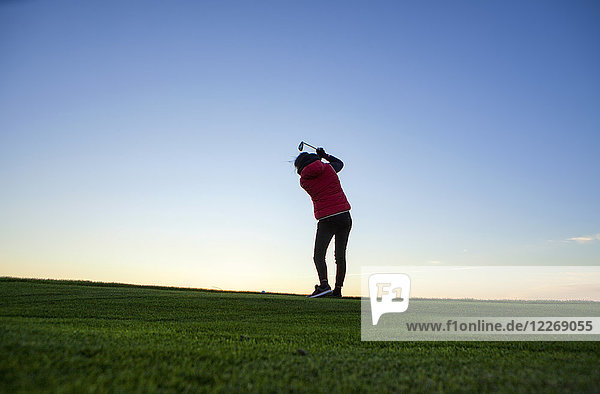 Frau schwingt Schläger beim Golfspielen