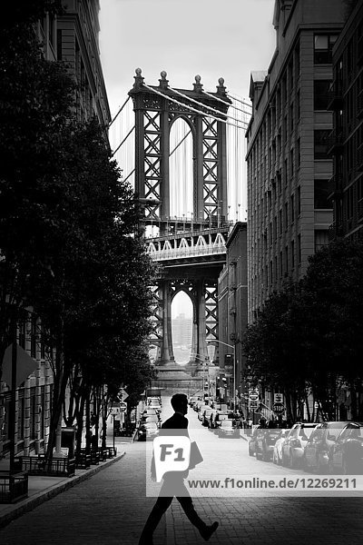Mann geht über eine schmale städtische Straße mit der Manhattan Bridge  New York  USA  im Hintergrund.