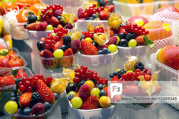 Hochwinkel-Nahaufnahme von Plastikschalen mit einer Auswahl von Sommerfrüchten wie Erdbeeren  Johannisbeeren  Heidelbeeren und Trauben.
