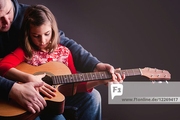 Father teaching daughter to play guitar