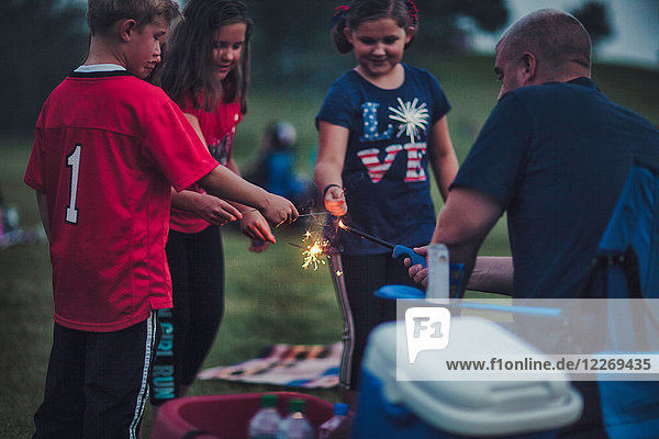Father lighting sparklers for group of children