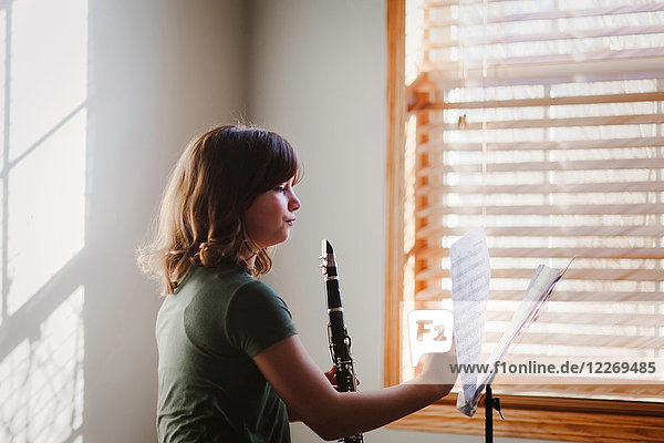 Girl at clarinet practice by window