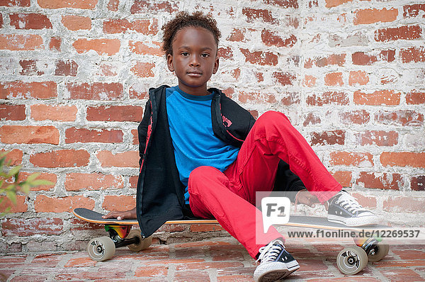Portrait of young boy sitting on skateboard