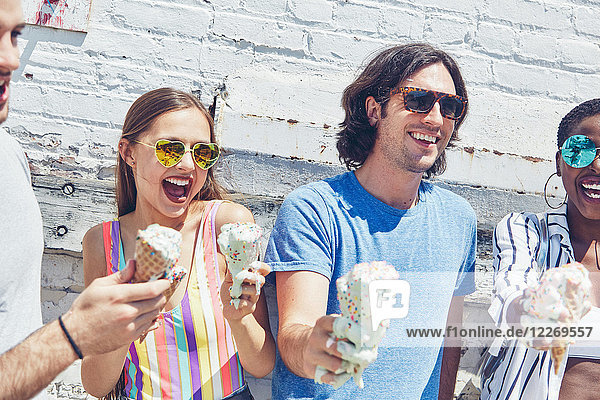 Young women and men holding melting ice cream cones  laughing