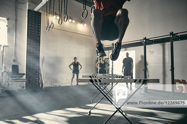 Man in mid air jumping hurdles in gym