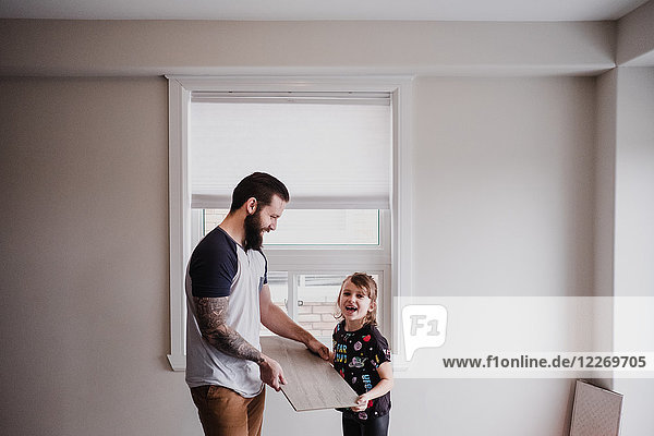 Girl helping father carry floor tile
