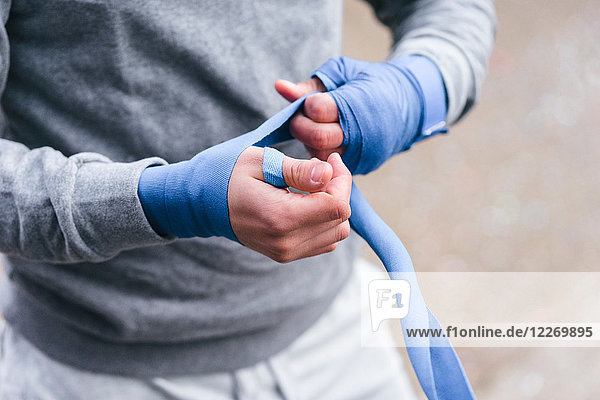 Junger männlicher Boxer trainiert im Freien  bandagiert die Hände mit Handumschlägen  Mittelteil