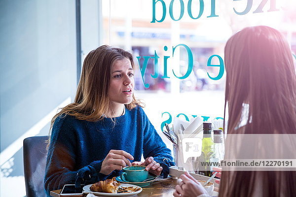 Zwei Freundinnen sitzen zusammen in einem Café und trinken Kaffee