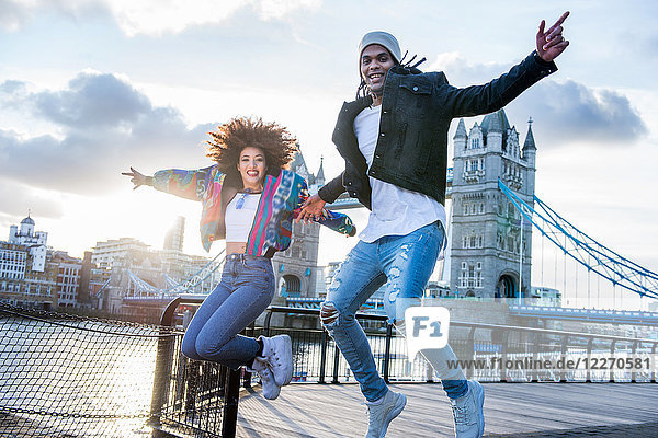 Young couple outdoors  jumping for joy  Tower Bridge in background  London  England  UK