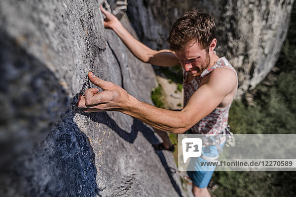 Young male rock climber climbing limestone rock face  Freyr  Belgium  high angle view