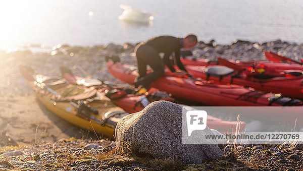 Mann bereitet Seekajak am Strand vor,  Narsaq,  Kitaa,  Grönland