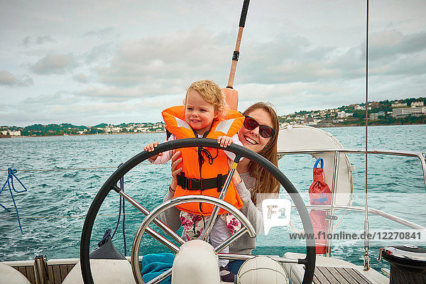 Frau steuert Yacht mit Kleinkind Tochter  Portrait  Devon  UK