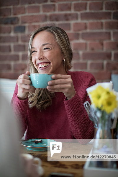 Frau sitzt im Café  trinkt Kaffee  lächelt