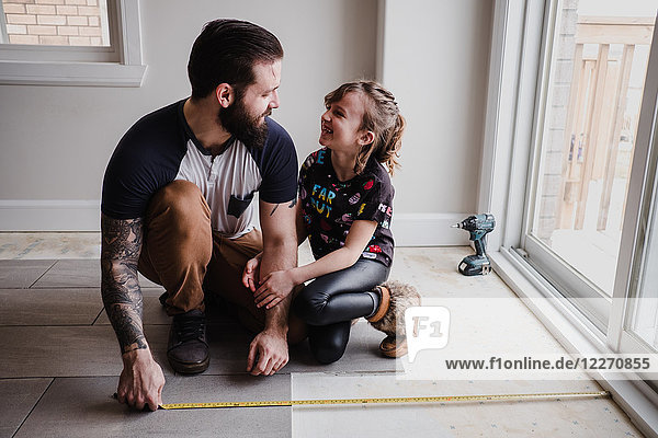Mädchen hilft Vater beim Verlegen von Bodenfliesen