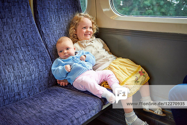 Weibliches Kleinkind sitzt mit kleiner Schwester im Zug
